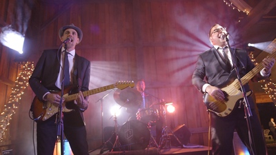 E3 band performing live on stage for wedding reception in a barn