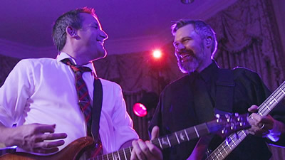 Real Geniuses The guitar and bass player have fun playing music in a ballroom